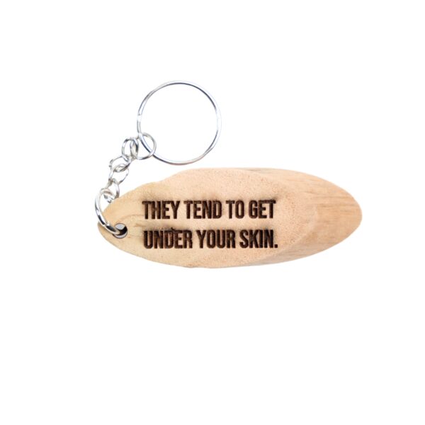 Togo Driftwood Keychain. “They tend to get under your skin.” front quote and Fortress Mountain, Alberta filming location of Togo longitude and latitude “44.3369° N, 109.7980° W” on the back.